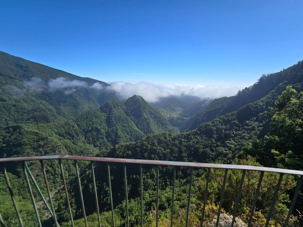 Uitzicht vanaf de miradouro op het eind van PR11 Vereda dos Balcões over groene valleien met laaghangende wolken op Madeira.
