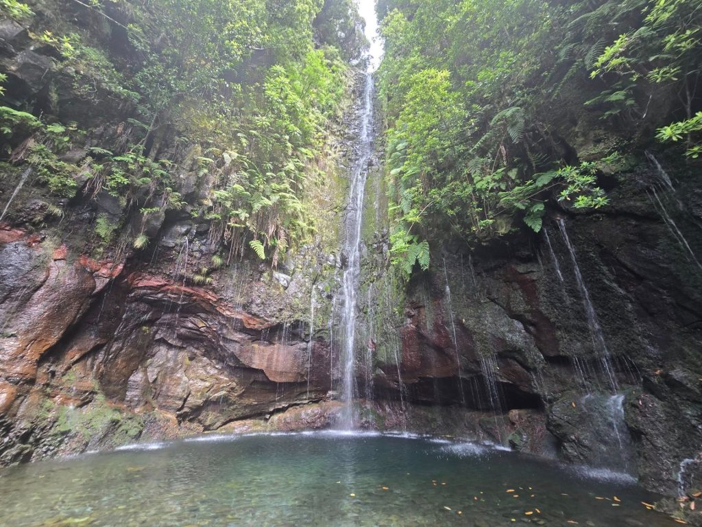 Op het eind van PR6 25 Fontes de Risco waterval die langs een mosrijke rotswand in een heldere poel uitkomt op Madeira.
