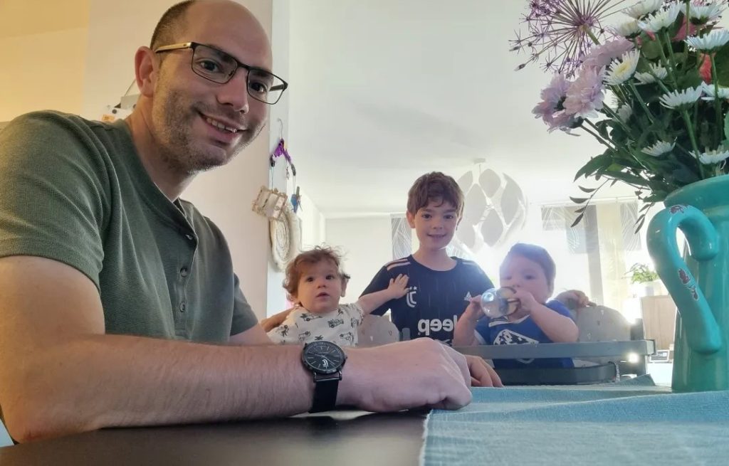 Alleenstaande vader zit aan tafel met zijn drie kinderen.