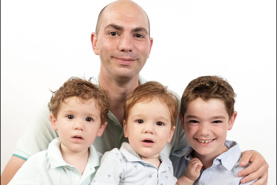 Alleenstaande vader met drie kinderen voor een witte achtergrond.