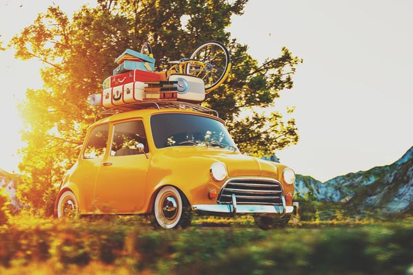Kleine gele auto volgeladen met koffers en fiets onderweg op vakantie