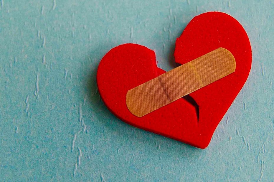 Gebroken rood hart met pleister als symbool voor emotionele pijn na een breuk