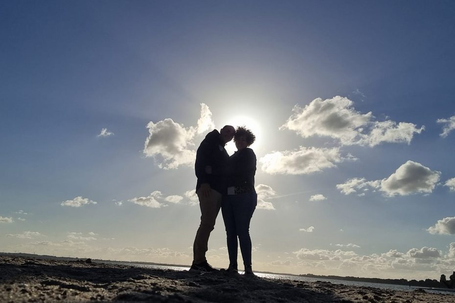 Koppel omhelst elkaar bij zonsondergang aan het strand – nieuwe relatie