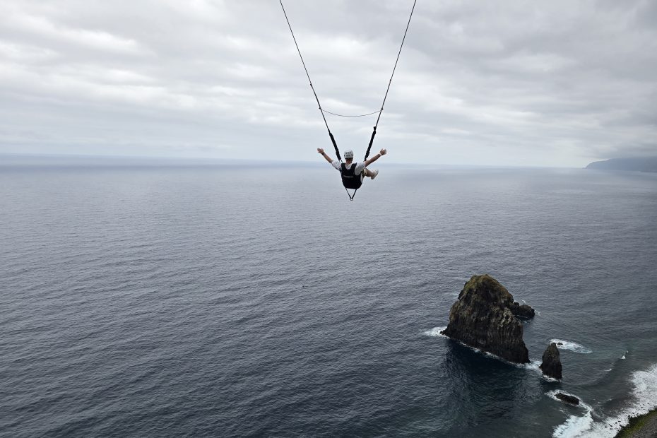 Rinaldo zweeft met open armen boven de oceaan aan de zipline van Madeira.