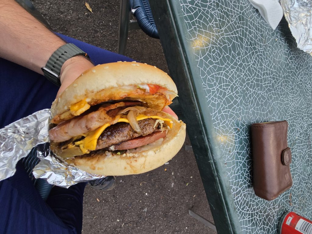 Close-up van een grote hamburger met bacon en kaas, gegeten op een terras in São Vicente.