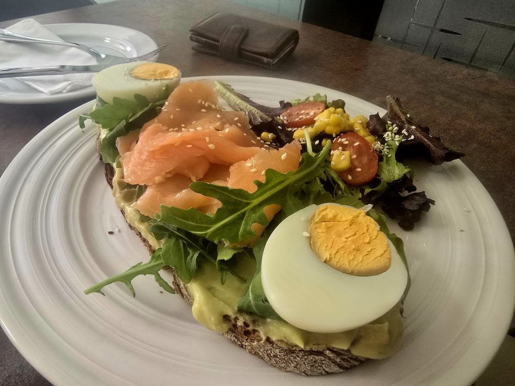 Avocado toast met gerookte zalm, ei en salade tijdens lunch in Funchal.