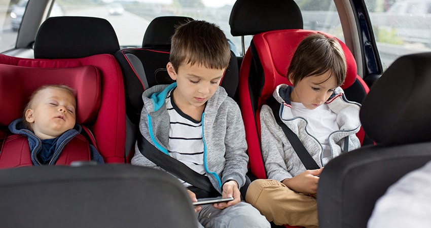 Drie kinderen op de achterbank tijdens de lange autorit naar Italië