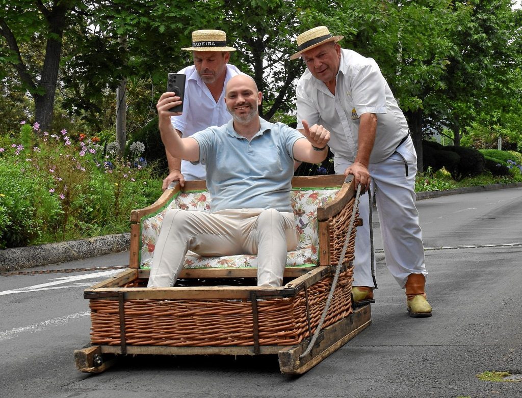 Selfie tijdens de traditionele toboggan-rit in Monte op Madeira, met bestuurders in wit uniform.