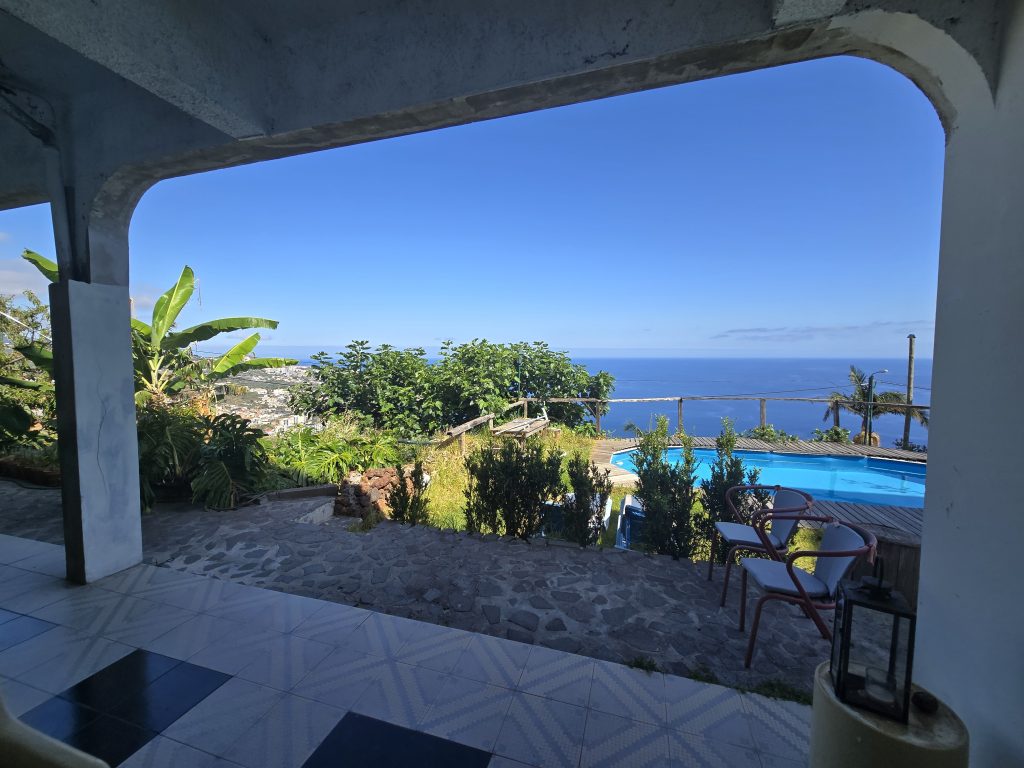 Uitzicht vanaf het verblijf op Madeira met zwembad en oceaan in de verte.