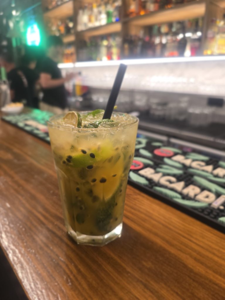 Verfrissende passievrucht-mojito aan de bar in Funchal met warme avondverlichting.