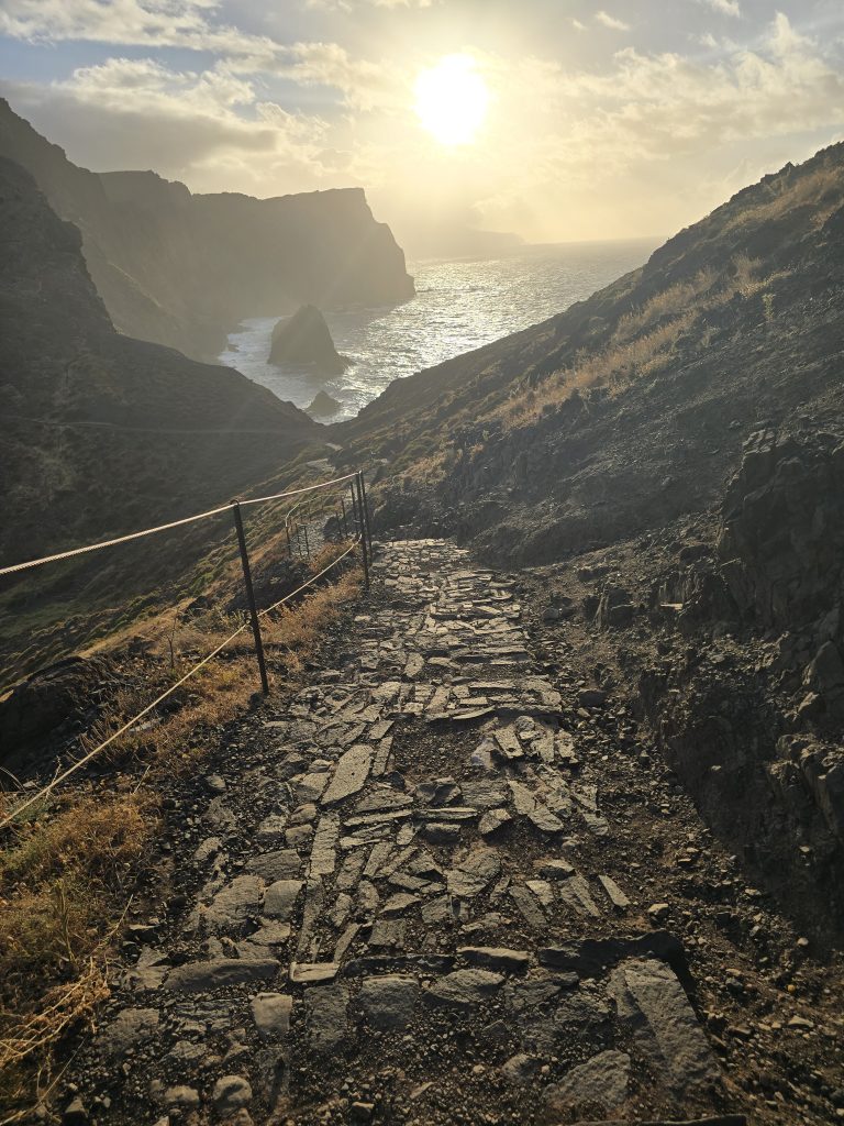 Zon door wolken op het geplaveide pad met kustlijn op de achtergrond