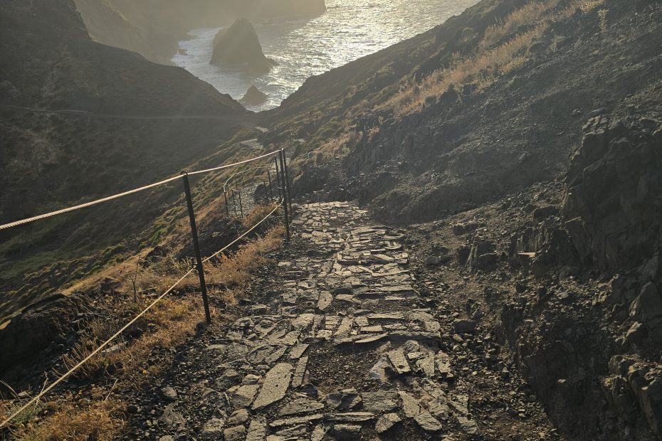 Zon door wolken op het geplaveide pad met kustlijn op de achtergrond